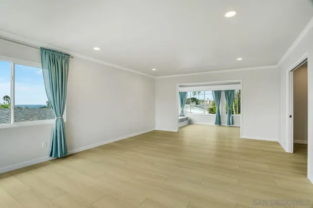 a view of an empty room with window and wooden floor