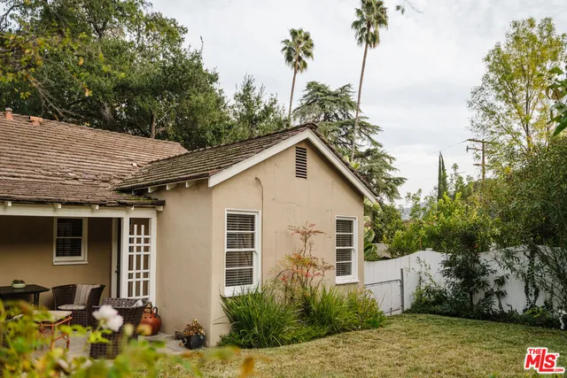 a view of a yard in front of a house with large trees