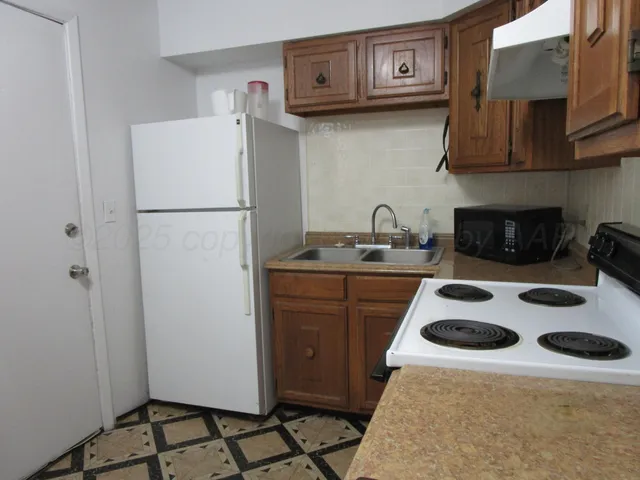 a kitchen with a sink a refrigerator and cabinets
