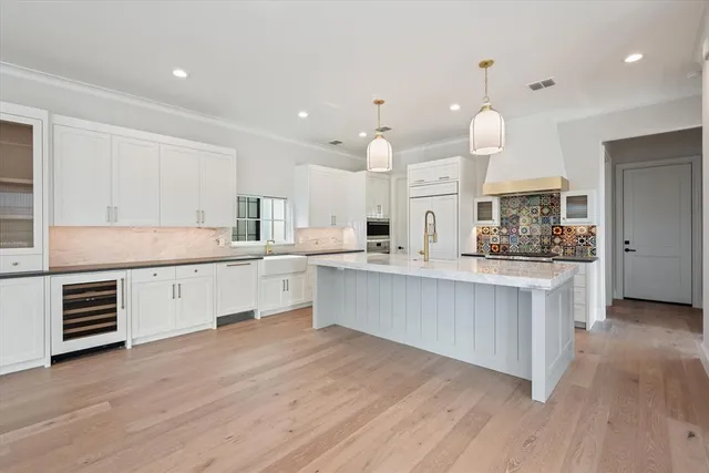 a large kitchen with granite countertop a stove a sink a center island and wooden floor