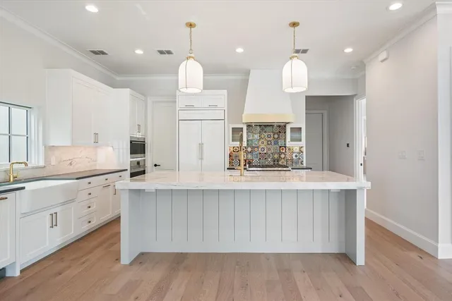 a large white kitchen with a sink a refrigerator and wooden floor