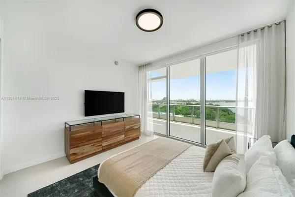 a bedroom with a bed and a flat tv screen next to a window