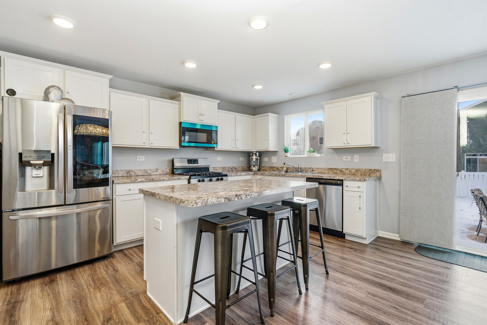 434 Stonebrook Drive Romeoville, IL 60446 - Photo 11 of 38 a kitchen with stainless steel appliances granite countertop a table chairs refrigerator and a sink