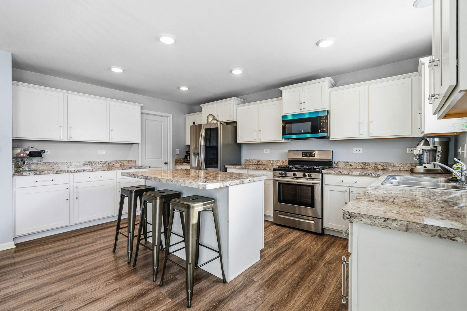 434 Stonebrook Drive Romeoville, IL 60446 - Photo 10 of 38 a kitchen with stainless steel appliances granite countertop a stove top oven a sink dishwasher and a refrigerator with wooden floor
