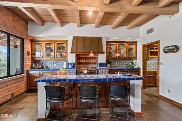 a dining hall with stainless steel appliances kitchen island granite countertop a table chairs in it and wooden floors
