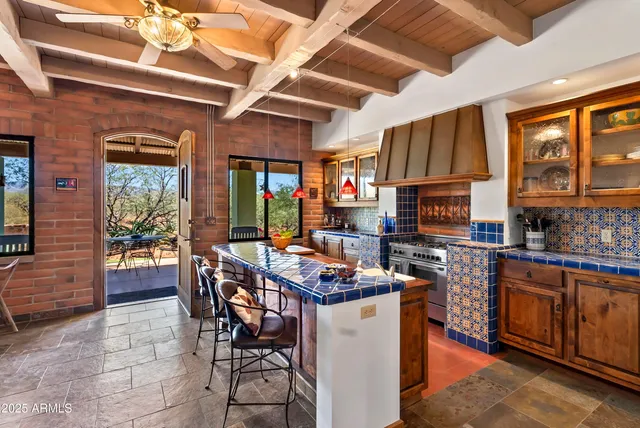 a room with stainless steel appliances kitchen island granite countertop a stove a sink dishwasher and a dining table with wooden cabinet