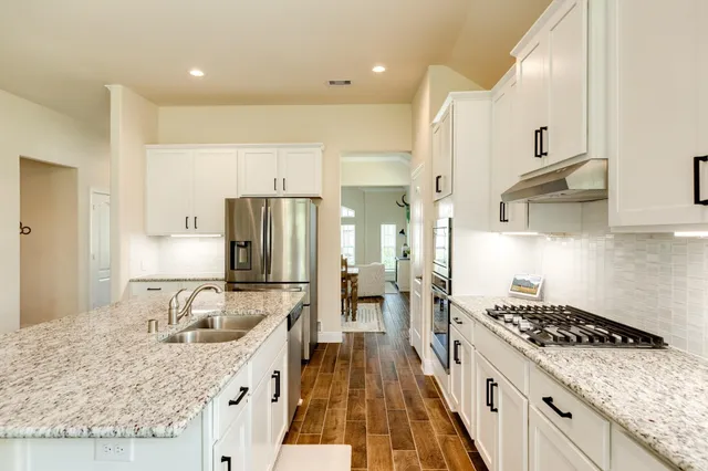a kitchen with kitchen island granite countertop a sink stove refrigerator and cabinets
