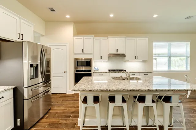 a kitchen with stainless steel appliances granite countertop a refrigerator and a sink