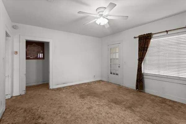 an empty room with windows and fan