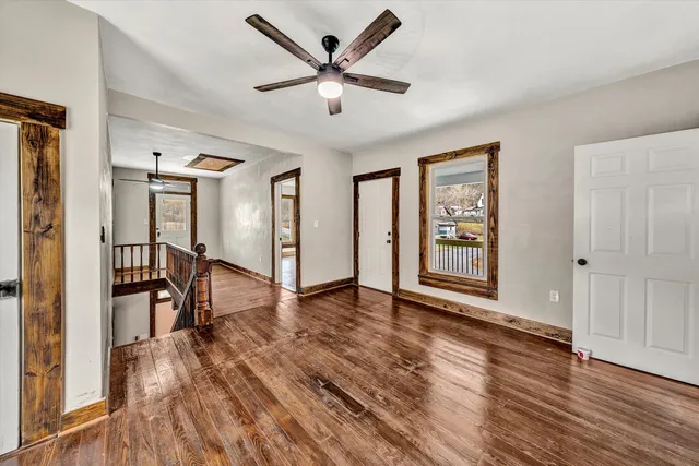 a view of an empty room with window wooden floor and a ceiling fan