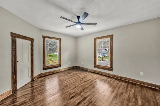a view of an empty room with a window and wooden floor