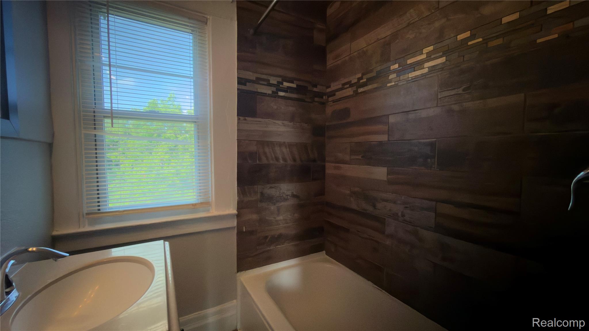9426 John R Street Detroit, MI 48202 - Photo 12 of 17 Bathroom featuring wood-look plank wall tile with a decorative accent band, a white bathtub, and a single-pane window with white blinds
