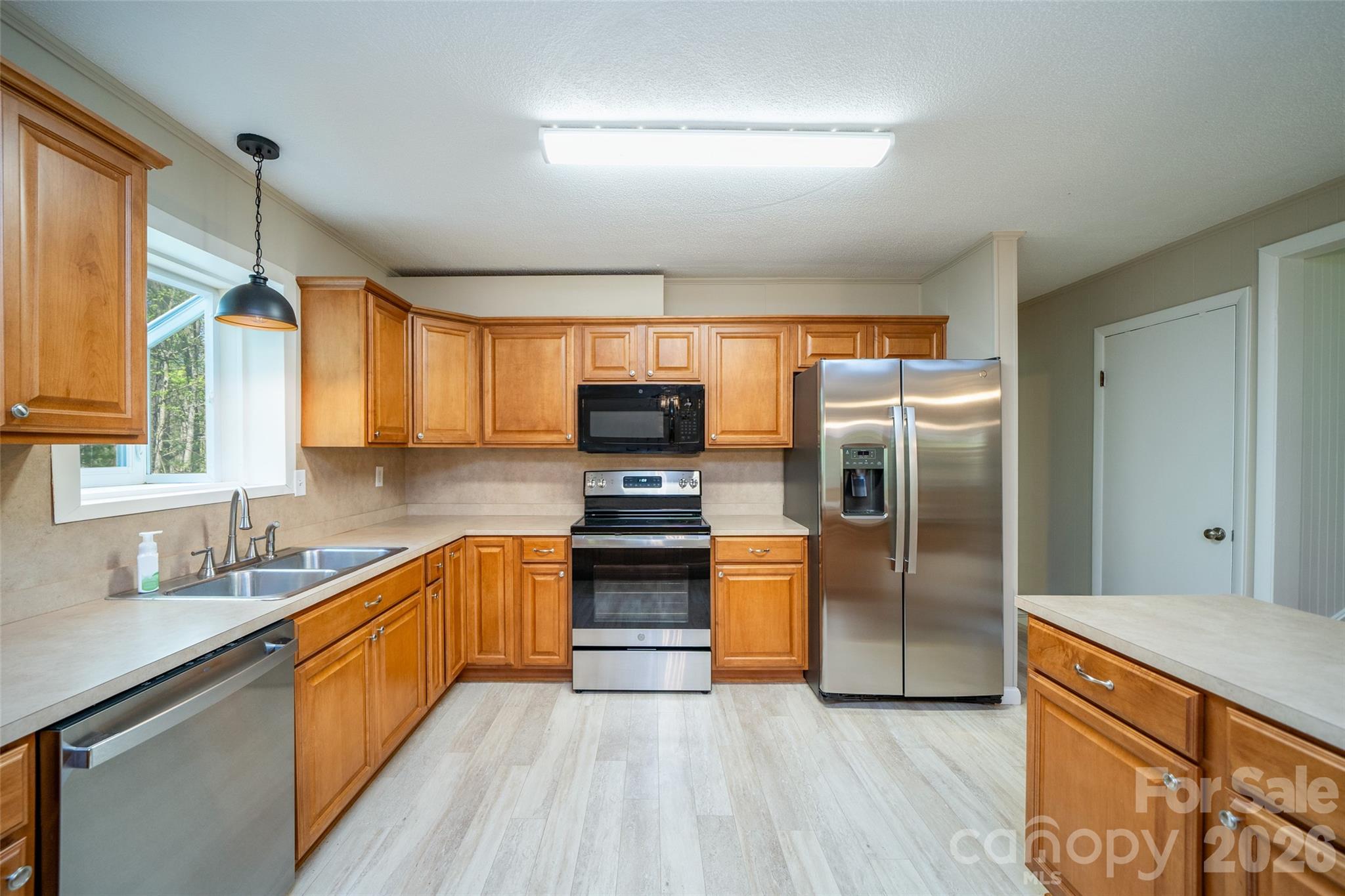 145 Jeter Mountain Road Hendersonville, NC 28739 - Photo 8 of 13 a large kitchen with stainless steel appliances granite countertop a refrigerator a sink dishwasher a oven with wooden cabinets and floor