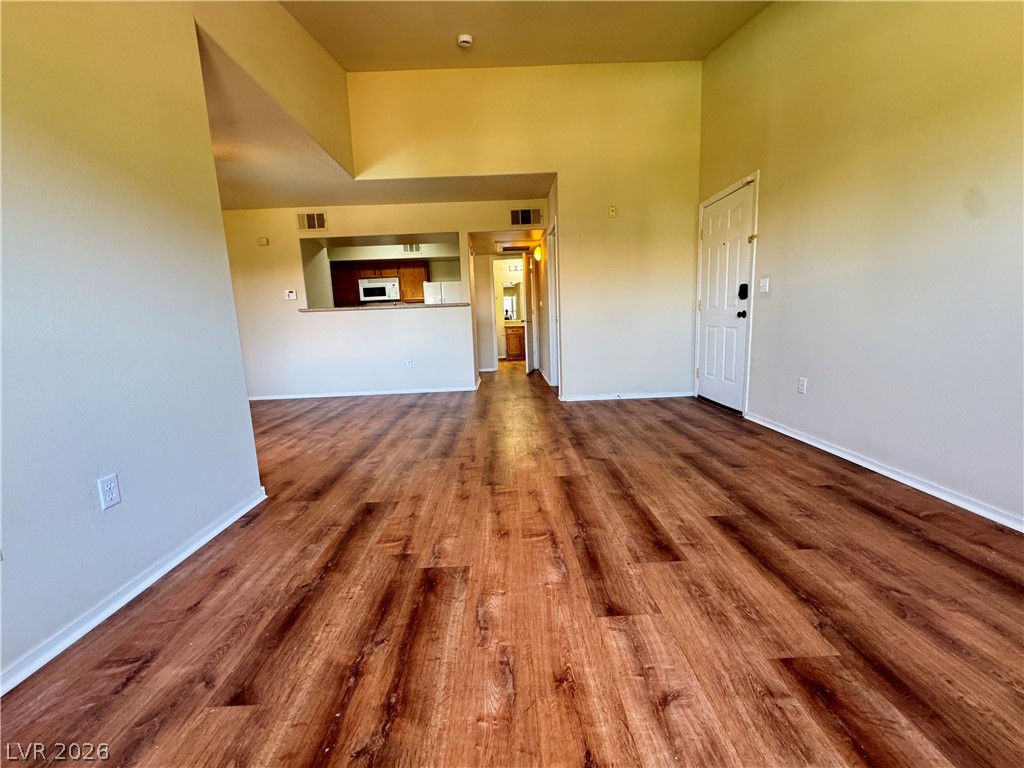 7255 West Sunset Road, Unit 2111 Las Vegas, NV 89113 - Photo 7 of 33 Warm wood-look flooring extends through this airy living area, leading to a convenient kitchen pass-through.