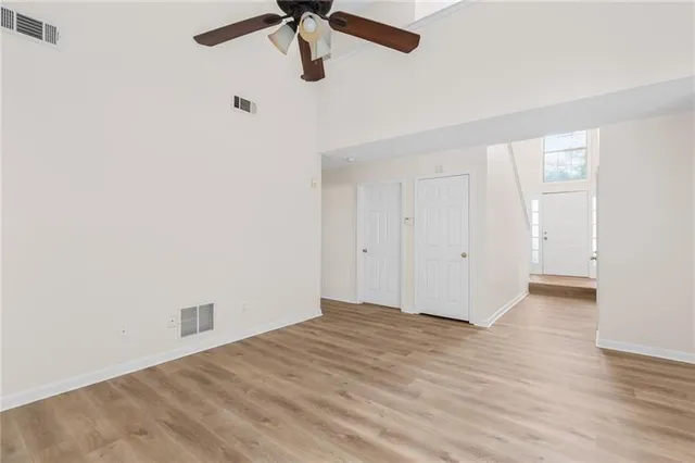 an empty room with a ceiling fan and wooden floor