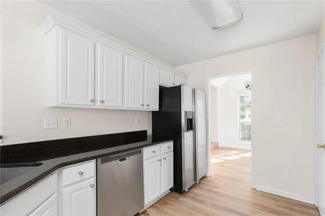 a kitchen with granite countertop white cabinets and stainless steel appliances