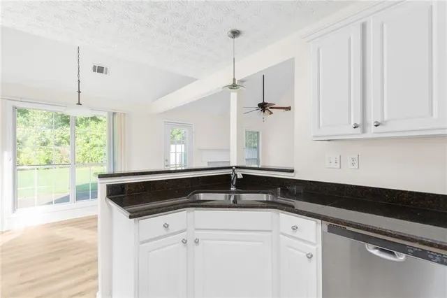 a kitchen with granite countertop white cabinets white appliances and a wide window