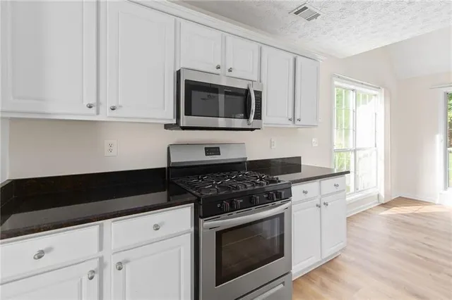 a kitchen with white cabinets and black appliances
