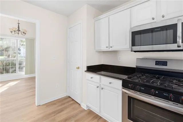 a kitchen with stainless steel appliances granite countertop white cabinets and black stove top oven