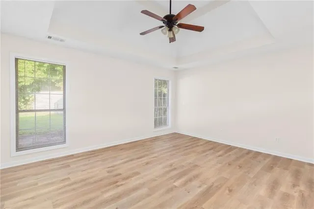 a view of empty room with wooden floor and fan