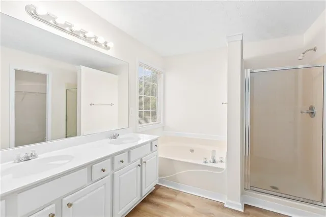 a bathroom with a granite countertop double vanity sink a mirror and a bathtub