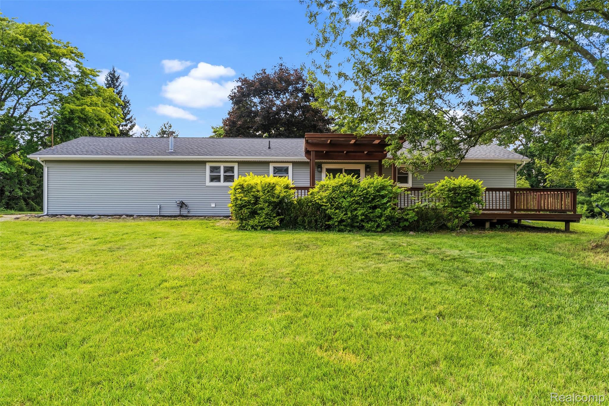 9200 Hickory Ridge Road Holly, MI 48442 - Photo 28 of 33 Expansive backyard featuring a manicured lawn, a full-length wooden deck, and a wooden pergola