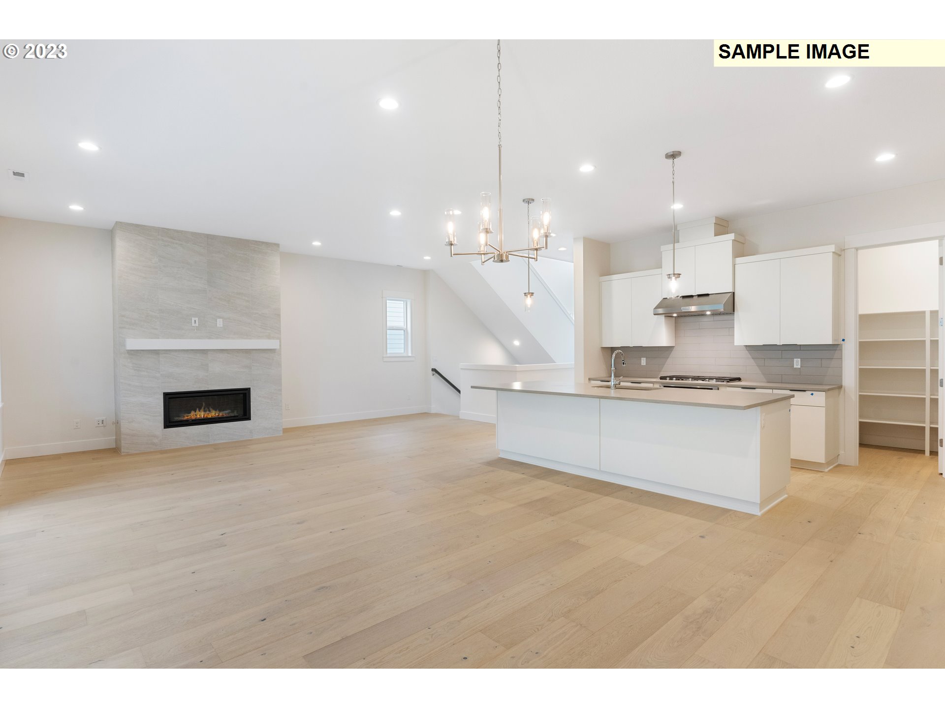 16060 Northwest Holman Way, Unit L79 Portland, OR 97229 - Photo 4 of 33 a large kitchen with kitchen island a stove a sink dishwasher and a fireplace with wooden floor