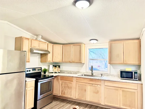 a kitchen with granite countertop a sink stainless steel appliances and white cabinets