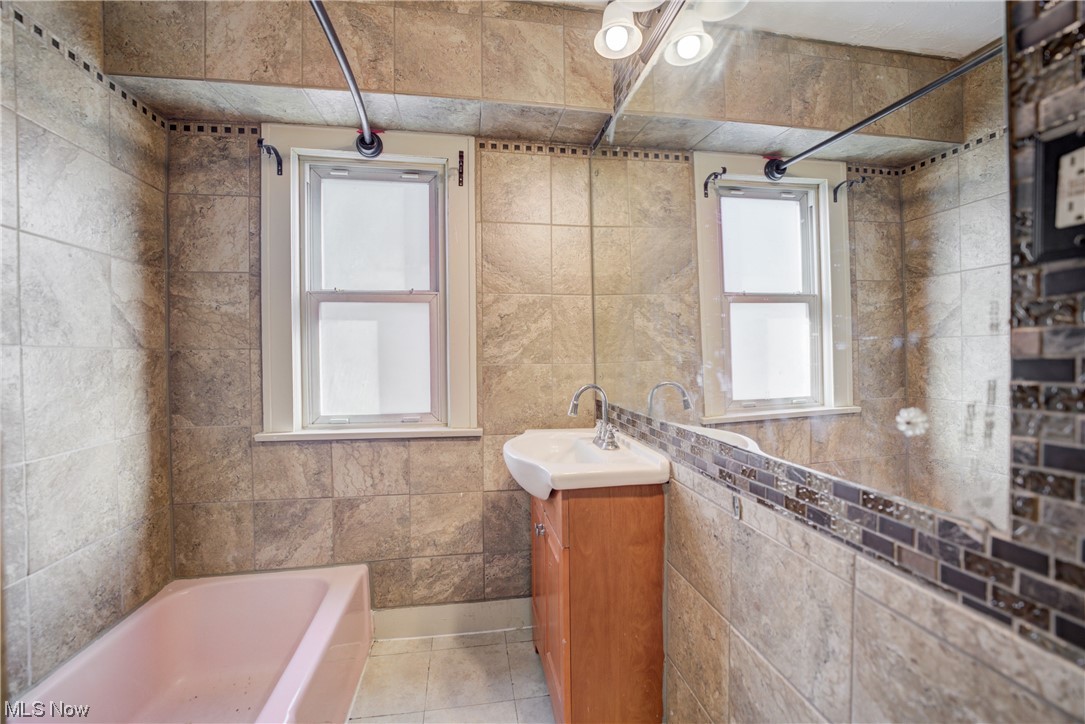 14202 Glenside Road Cleveland, OH 44110 - Photo 12 of 41 Bathroom with tiled shower / bath, oversized vanity, tile floors, and tile walls
