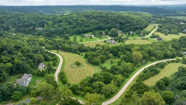 an aerial view of residential house with outdoor space and trees all around
