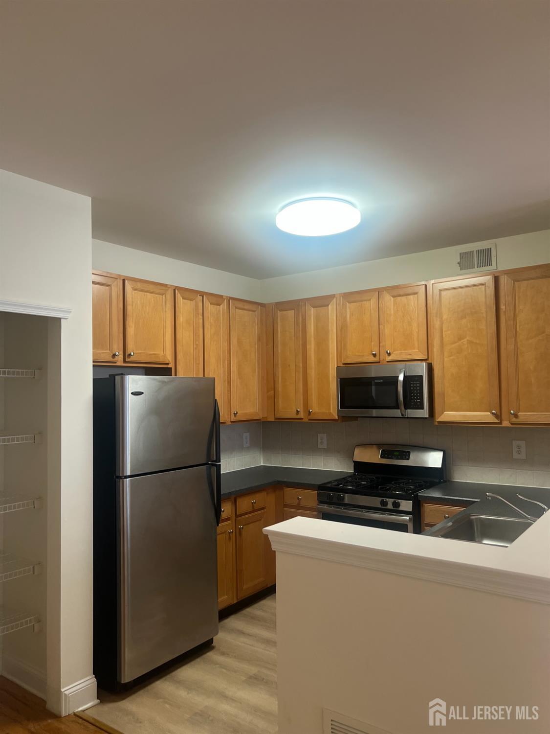 17 Burdak Road Sayreville, NJ 08859 - Photo 2 of 19 a kitchen with a refrigerator a microwave a sink and a stove