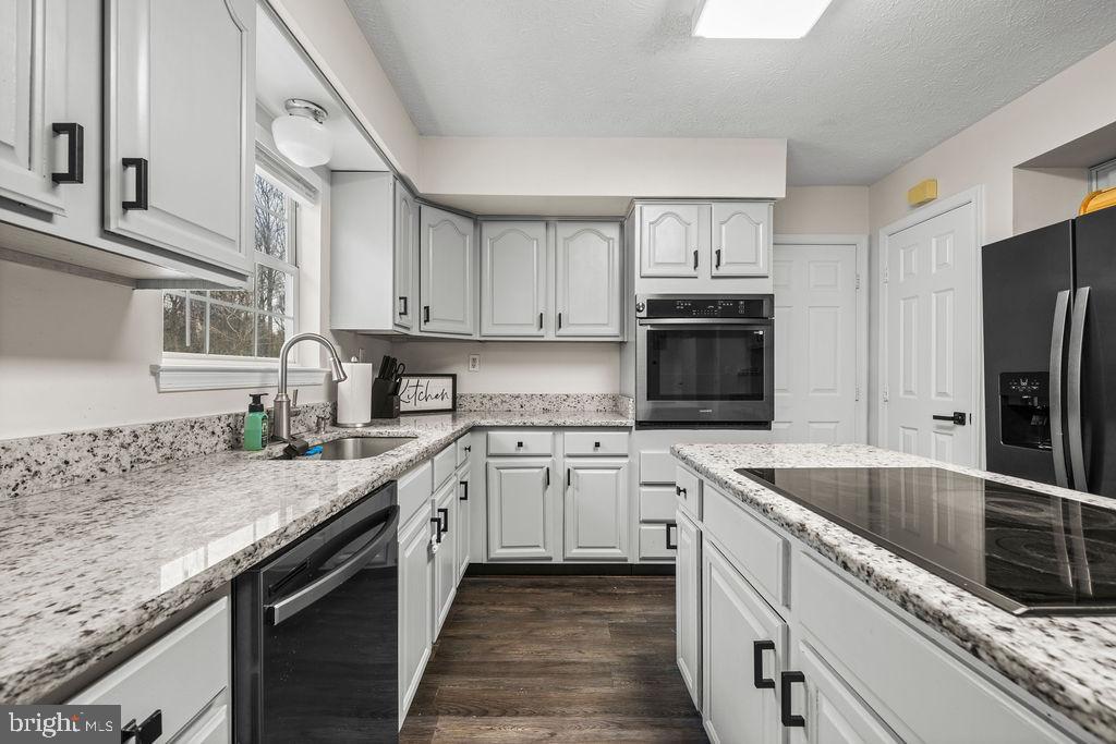 9803 Bald Hill Road Bowie, MD 20721 - Photo 20 of 55 a kitchen with granite countertop a sink stainless steel appliances and white cabinets