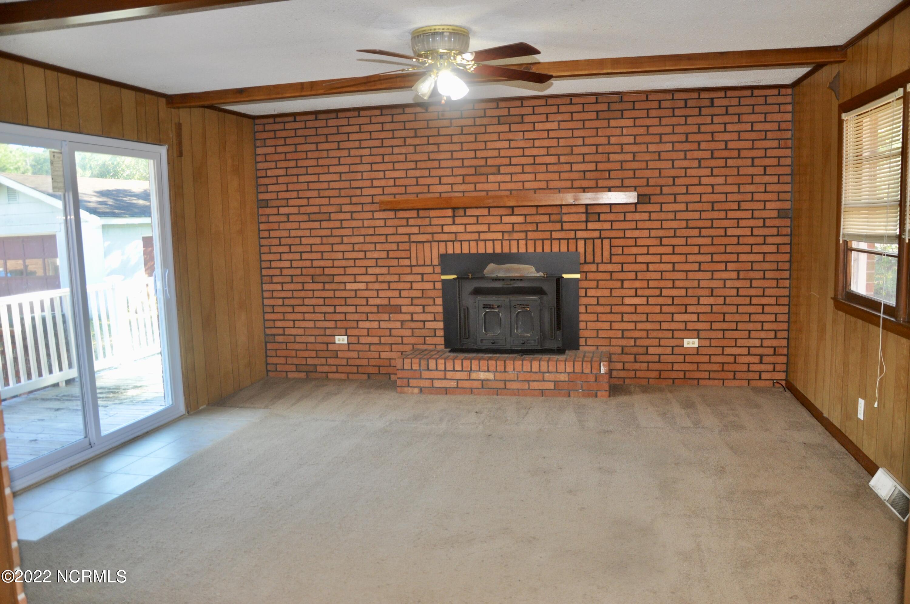 2308 Rockhill Road Castle Hayne, NC 28429 - Photo 9 of 31 Large den with exposed brick, wooden beams, and wood burning stove