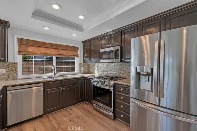 a kitchen with stainless steel appliances granite countertop a refrigerator a sink dishwasher a stove and a refrigerator with wooden floor