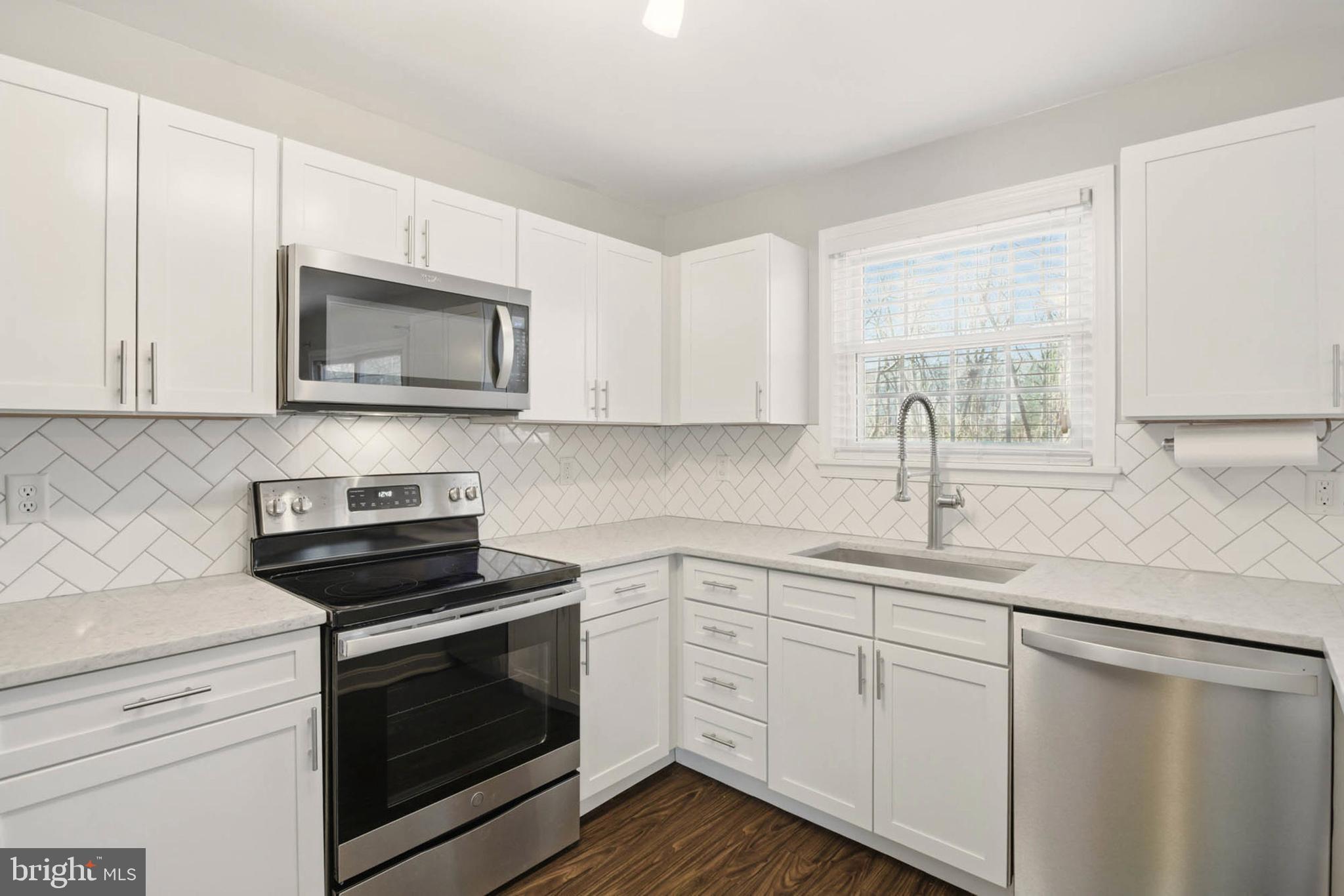 7812 Solari Court Pasadena, MD 21122 - Photo 3 of 30 a kitchen with granite countertop white cabinets appliances a sink and a window