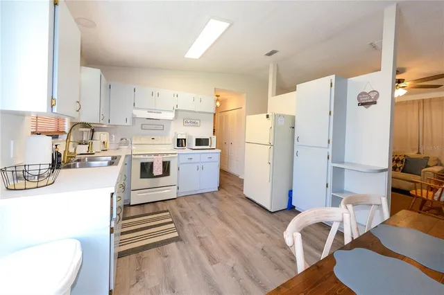 a kitchen with a refrigerator a stove and white cabinets with wooden floor
