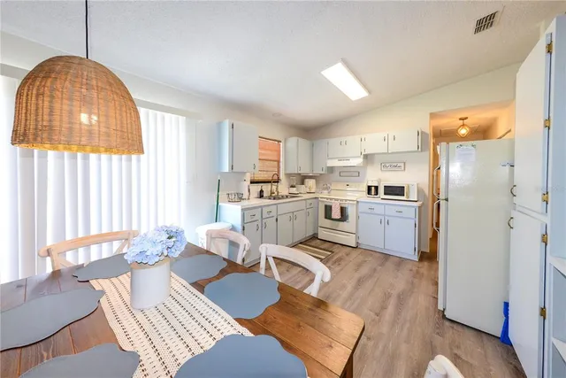 a kitchen with a refrigerator a sink dishwasher a dining table and chairs with wooden floor