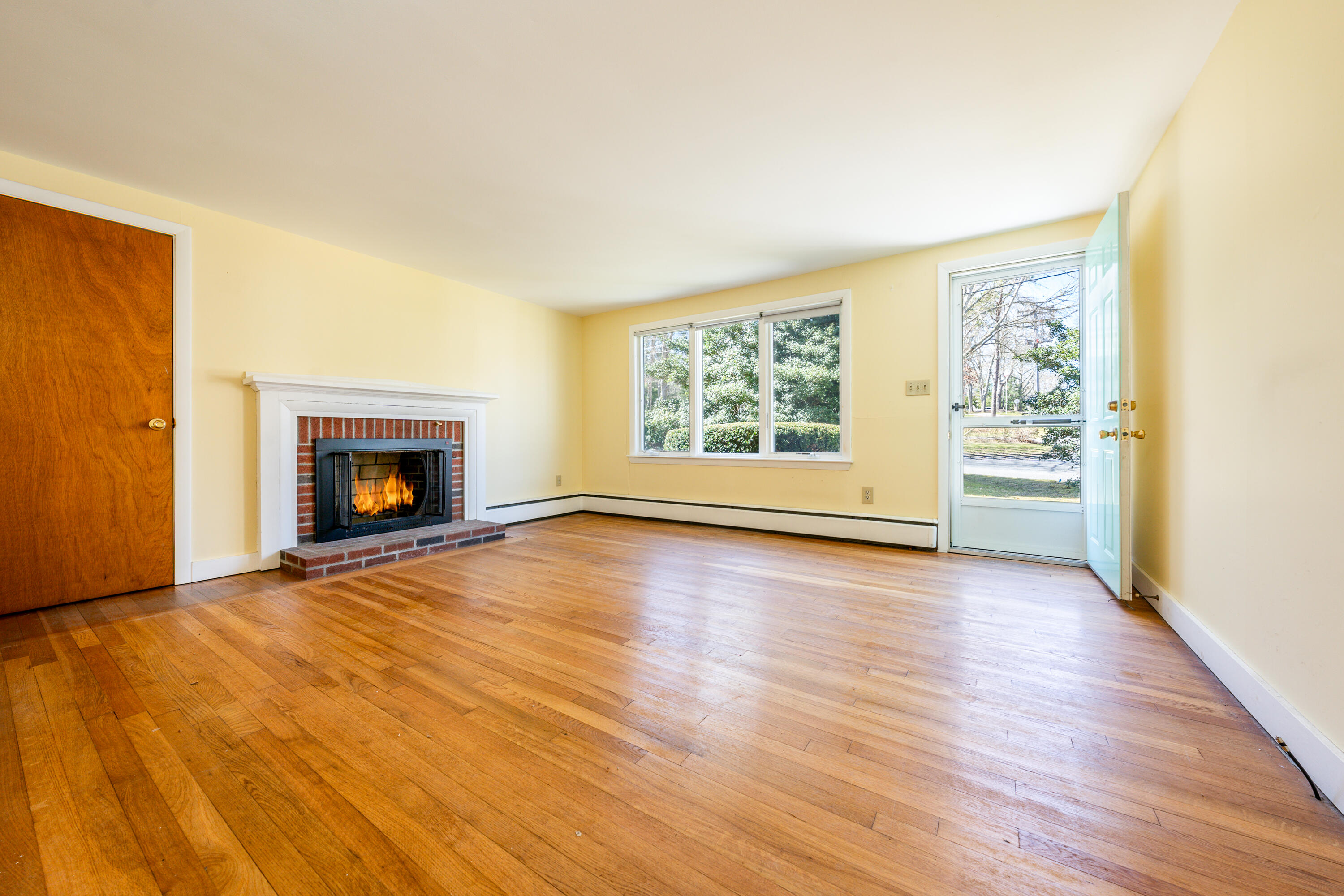 54 Hinckley Circle Osterville, MA 02655 - Photo 2 of 30 an empty room with wooden floor a fireplace and windows
