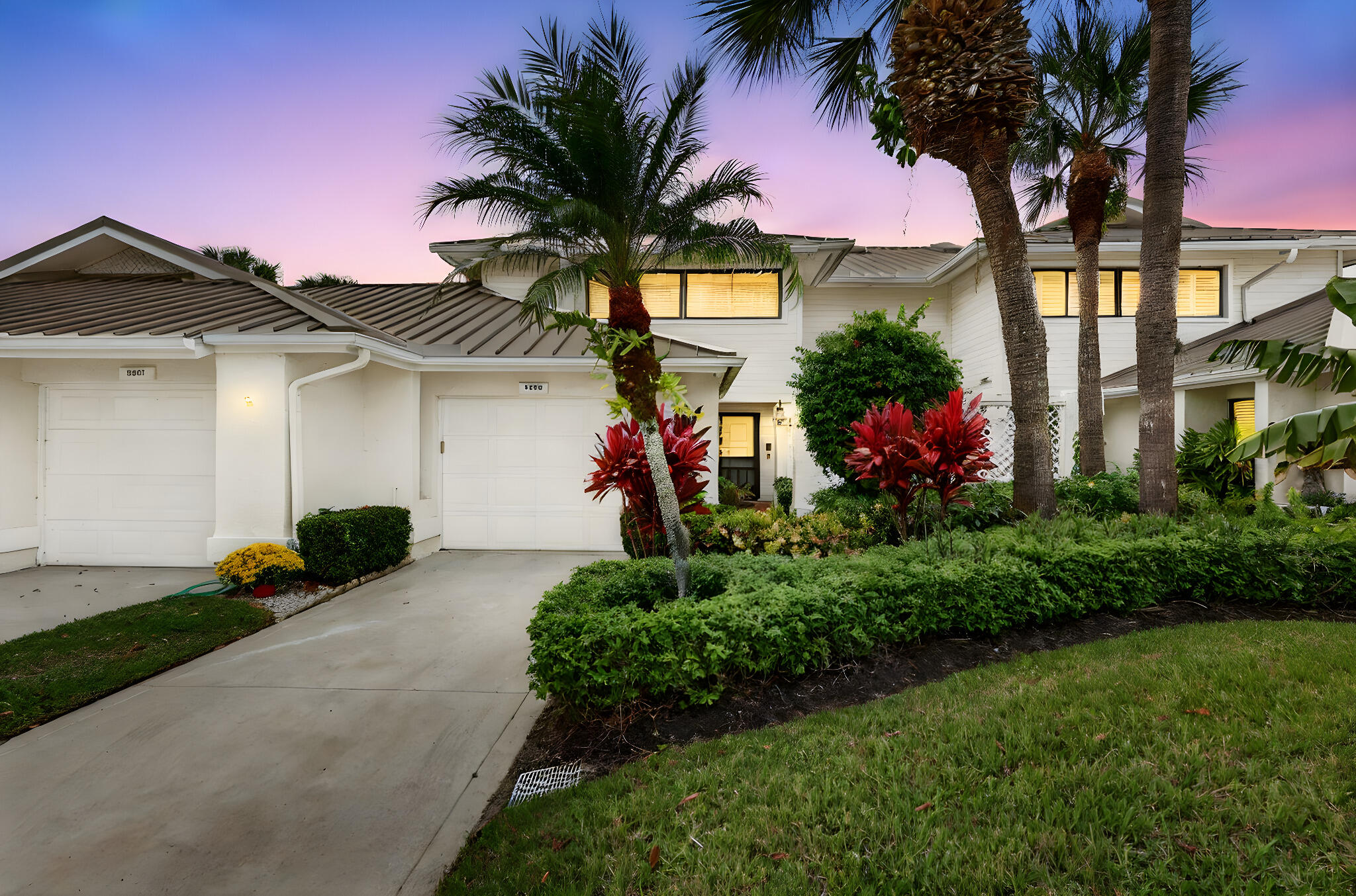 a front view of a house with a yard and potted plants