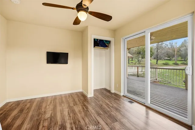 a view of empty room with wooden floor and fan
