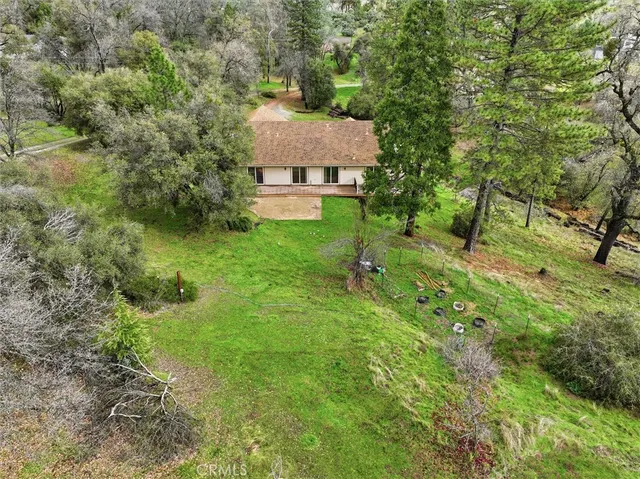an aerial view of residential house with outdoor space and trees all around