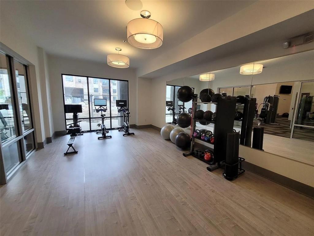 2700 Old Denton Road, Unit 2238 Carrollton, TX 75007 - Photo 7 of 21 Dedicated fitness space featuring wood-finish flooring, full-height mirrored wall, and large windows providing natural light
