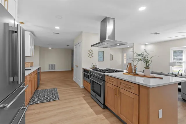 a kitchen with stainless steel appliances granite countertop a sink a stove a refrigerator a microwave a dining table and chairs with wooden floor