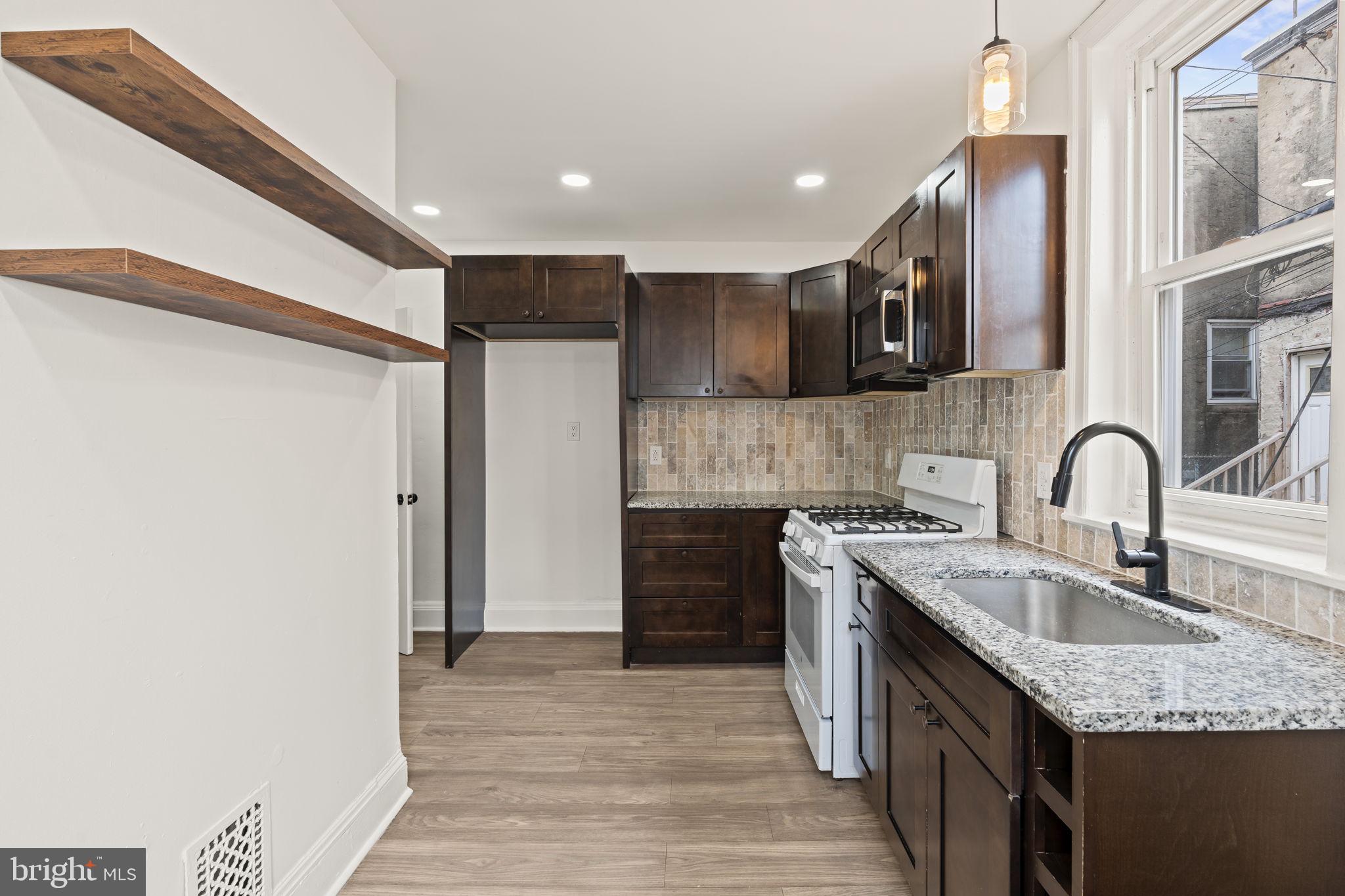 4466 North 3rd Street Philadelphia, PA 19140 - Photo 12 of 28 a kitchen with stainless steel appliances granite countertop a sink stove and refrigerator