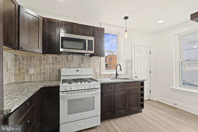 a kitchen with stainless steel appliances granite countertop a stove a sink and a microwave
