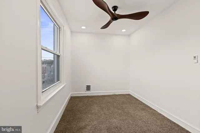an empty room with a window and a fan