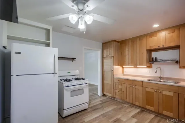 a kitchen with a refrigerator a sink and dishwasher a stove with wooden floor