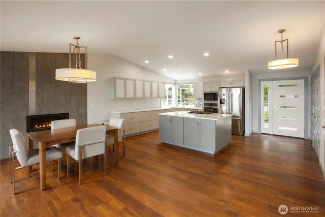 a kitchen with stainless steel appliances kitchen island granite countertop a dining table chairs and white cabinets