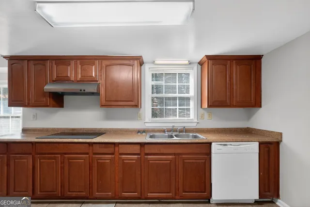 a kitchen with granite countertop a sink cabinets and stainless steel appliances