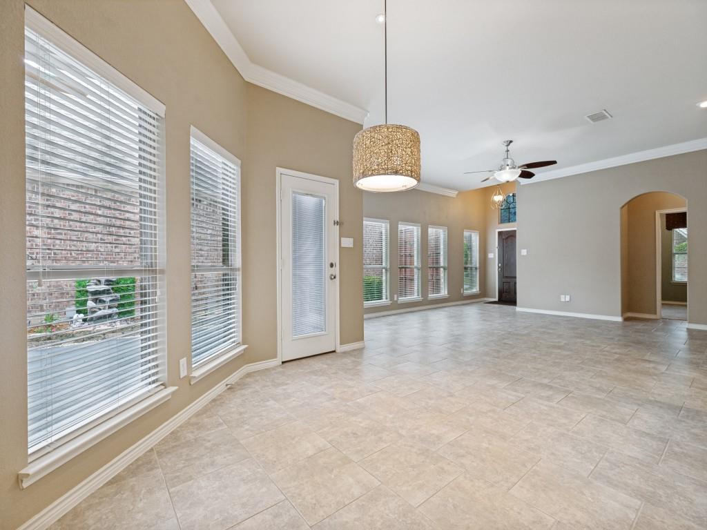 10032 Bell Rock Road Frisco, TX 75035 - Photo 6 of 23 Spacious living area featuring neutral tile flooring, high vaulted ceilings, and crown molding.